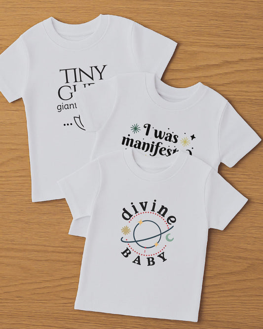 Three white t-shirts with printed text on a wooden surface